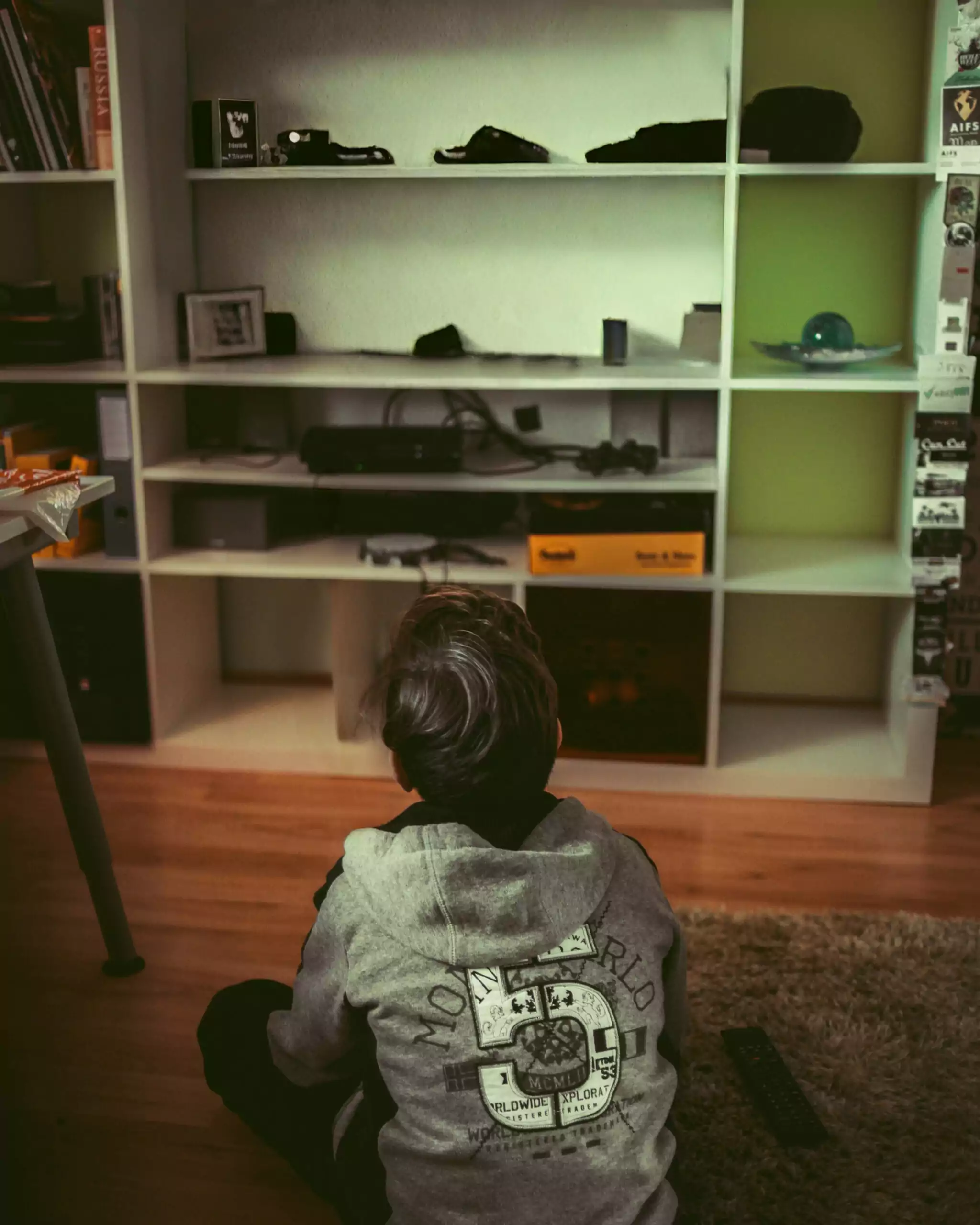 petit garçon de dos, assis parterre, en train de regarder la TV