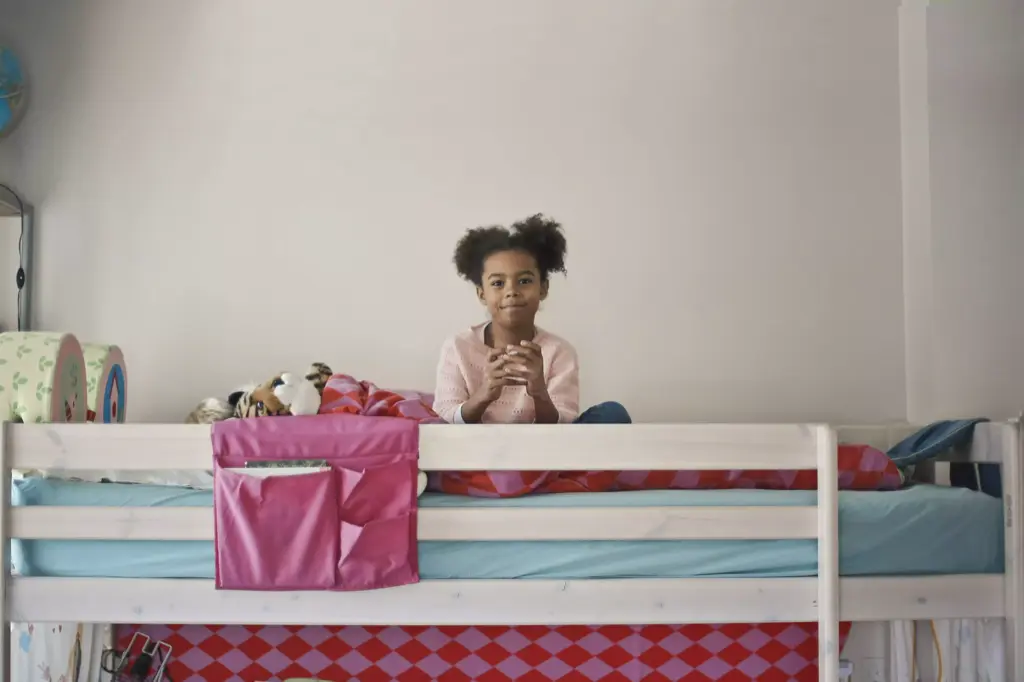 petite fille métisse dans son lit superposé en train de scroller sur son smartphone